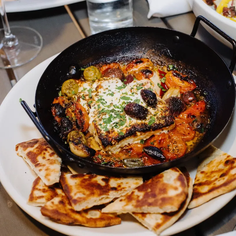 Baked feta with roasted tomatoes, olives, and grilled pita